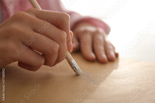 Woman correcting picture on paper with pencil eraser  closeup