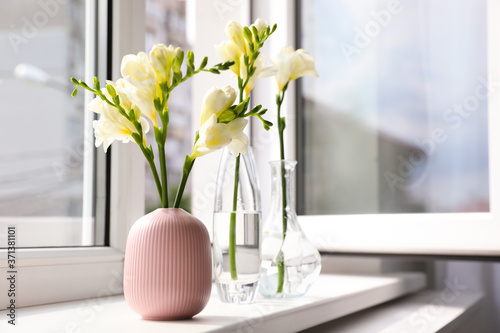 Beautiful white spring freesia flowers on window sill in room