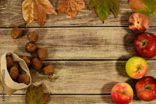 collection beautiful colorful autumn leaves, walnuts and apples on wooden background.