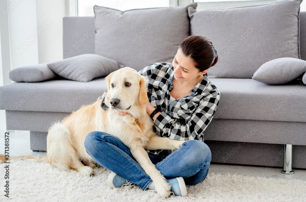 Happy woman petting cute dog in light apartment Happy woman petting cute dog in light apartment