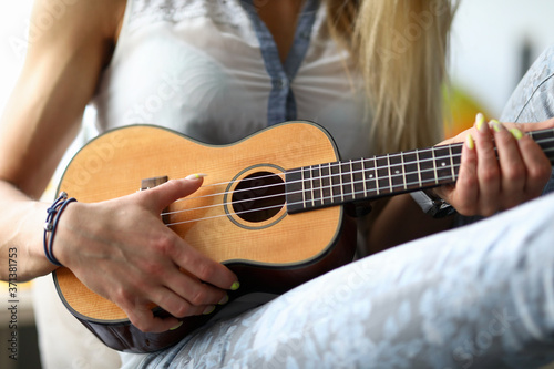 Female hands holding ukulele guitar learning how to play