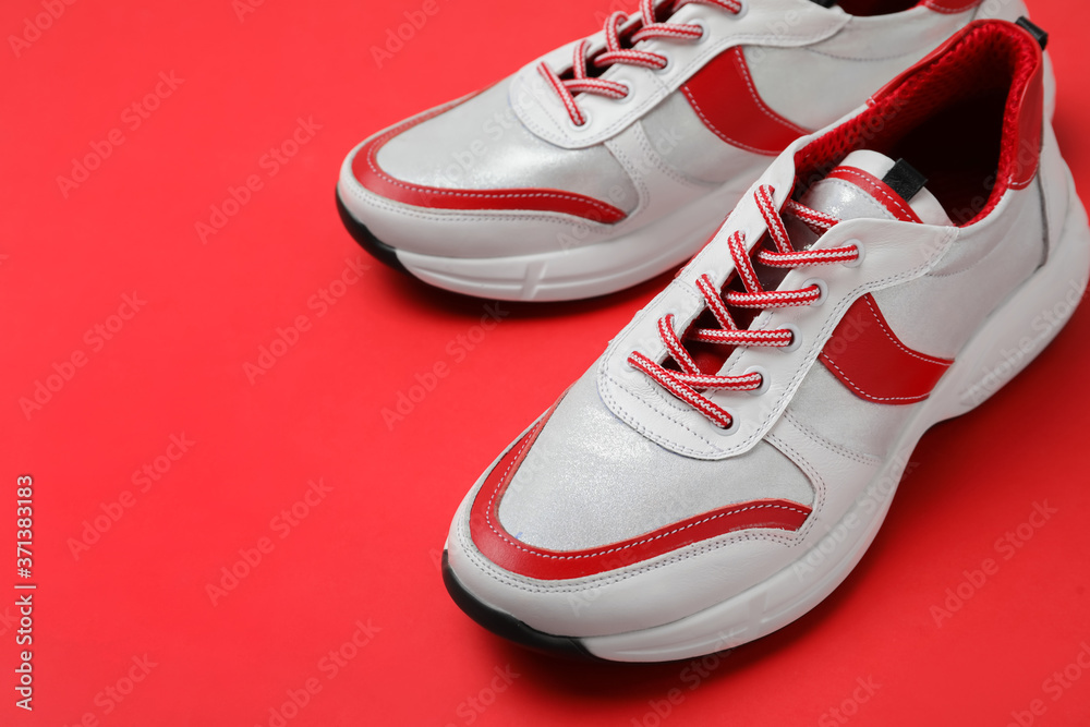 Pair of stylish sneakers on red background, closeup Pair of stylish sneakers on red background, closeup