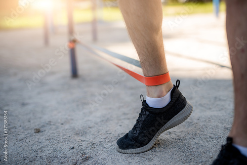 Male legs training with elastic rubber outdoors, close up © Ievgen Skrypko