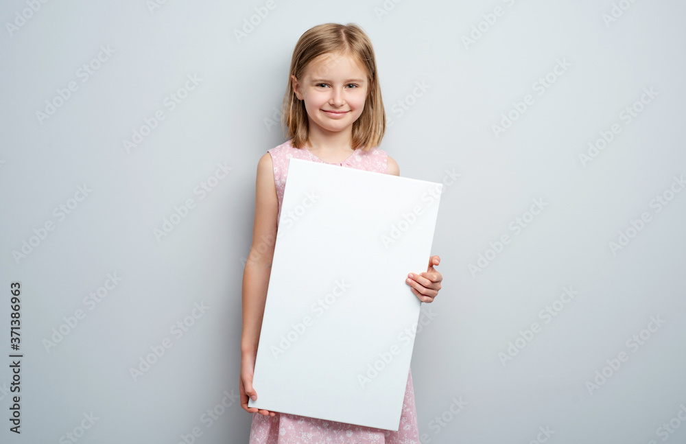 Little girl holding vertical empty placard on gray wall background Little girl holding vertical empty placard on gray wall background