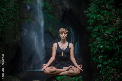 Yoga practice and meditation in nature. Woman practice near waterfall.