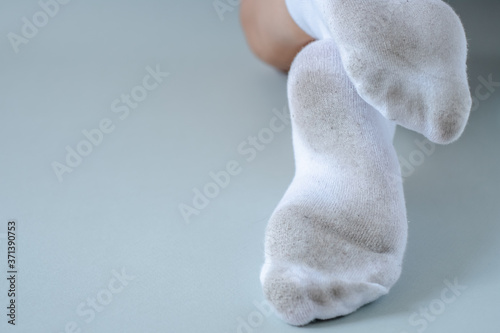 Pair of child feet in dirty stained white socks. dirty socks Pair of child feet in dirty stained white socks. Kid soiled socks while playing outdoors. Children clothes bleaching and.