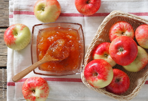 Top view.Autumn still life with apples. Apple jam surrounded by apples on a napkin on a wooden background photo