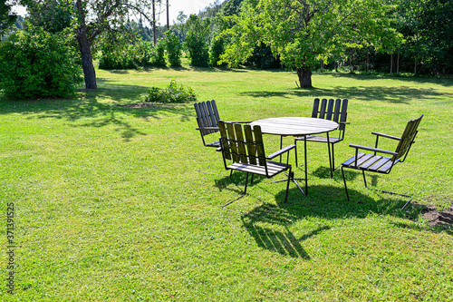 wooden garden table and four chairs on a green lawn