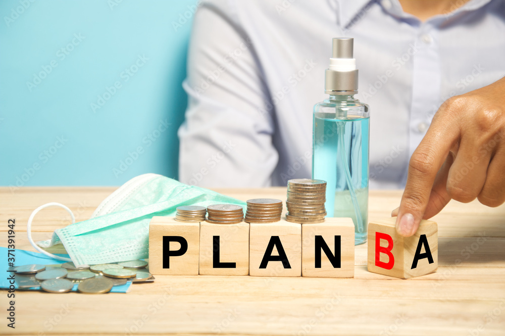 hand flipping wood cube from plan A to plan B when faced with financial problem during covid-19 crisis