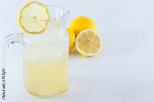 Lemon juice with ice in a glass jug Decorated with lemon slices With lemon cubes cut in half On a white backdrop