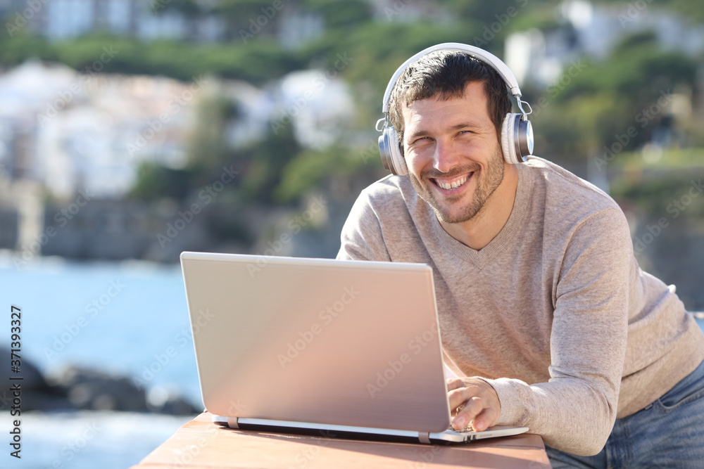 Man with headphones and laptop posing on the beach Man with headphones and laptop posing on the beach