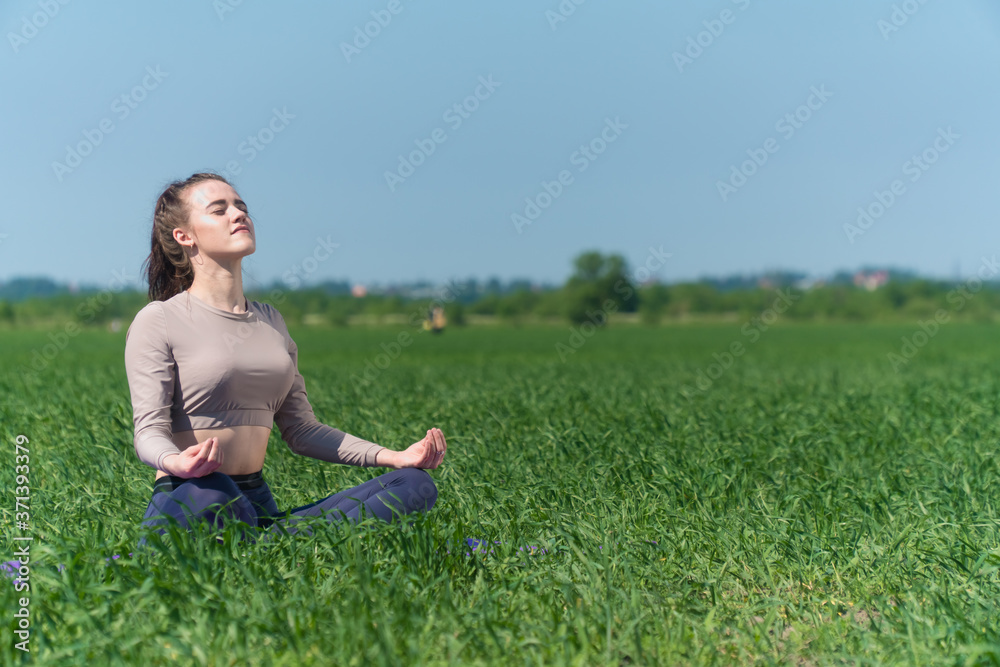 A young Caucasian girl practices yoga meditation in the fresh air. The concept of peace of mind. A young Caucasian girl practices yoga meditation in the fresh air. The concept of peace of mind.