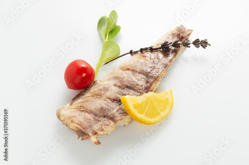 Fish fried on the grill and served on a plate with fresh vegetables photo