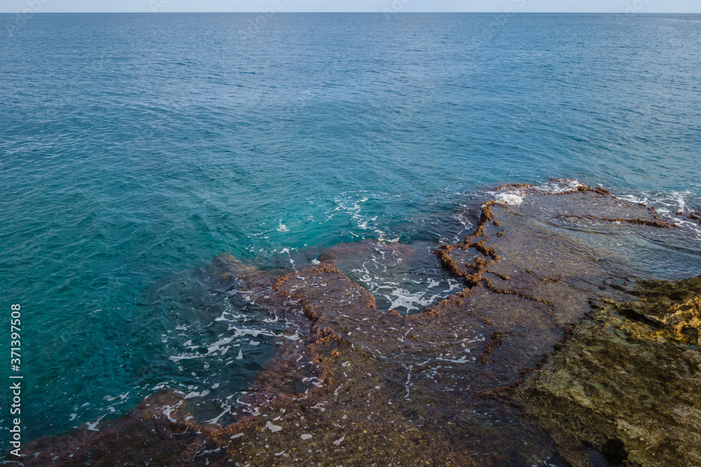 Shoreline reefs washing by waves. Form of stones very similar to travertines. Clear horizon & endless calm blue sea are on background. Shot in Kizkalesi, Mersin province, Turkey Shoreline reefs washing by waves. Form of stones very similar to travertines. Clear horizon & endless calm blue sea are on background. Shot in Kizkalesi, Mersin province, Turkey