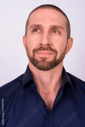 Face of handsome bald bearded businessman thinking and looking up
