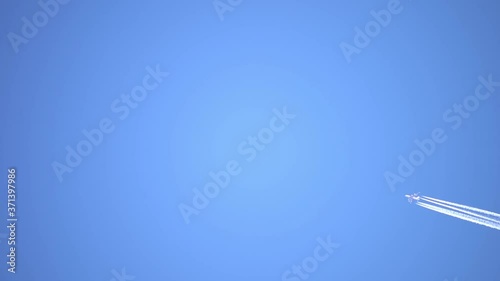 Aircraft contrail against clear blue sky, slow motion. Airplane flying high