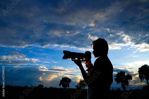 Silhouette of a man photographer with dslr camera during taking photos at sunset