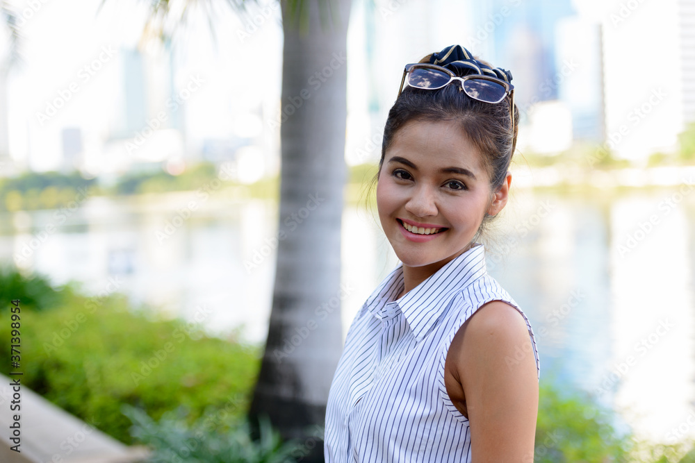 Happy young beautiful Asian woman at the park outdoors Happy young beautiful Asian woman at the park outdoors