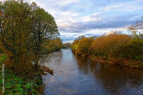 The River South Esk flowing slowly through the Countryside near to the Bridge of Dun, with the trees showing their Autumn Colours.