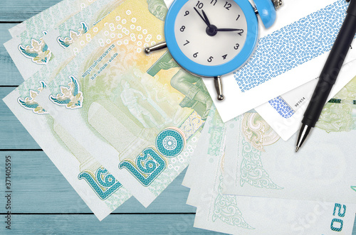 20 Thai Baht bills and alarm clock with pen and envelopes. Tax season concept, payment deadline for credit or loan. Financial operations using postal service photo