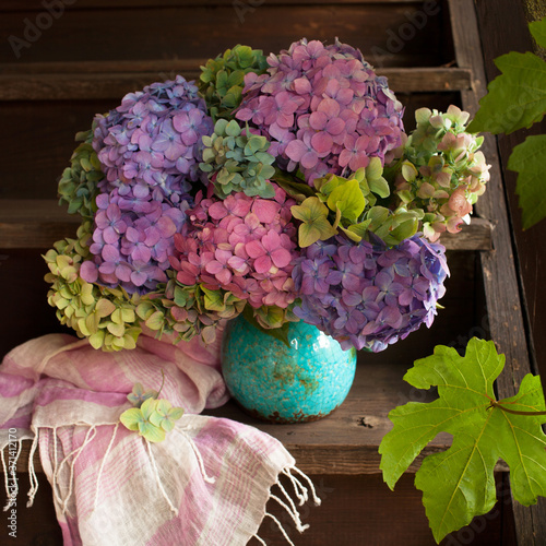 Fotografia, Obraz A multi-colored bouquet of hydrangeas in a vase on an old wooden staircase