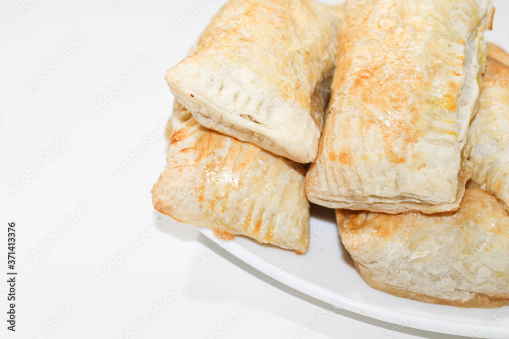 Fresh baked puff pastries on a white plate. Rich pastries on the table.