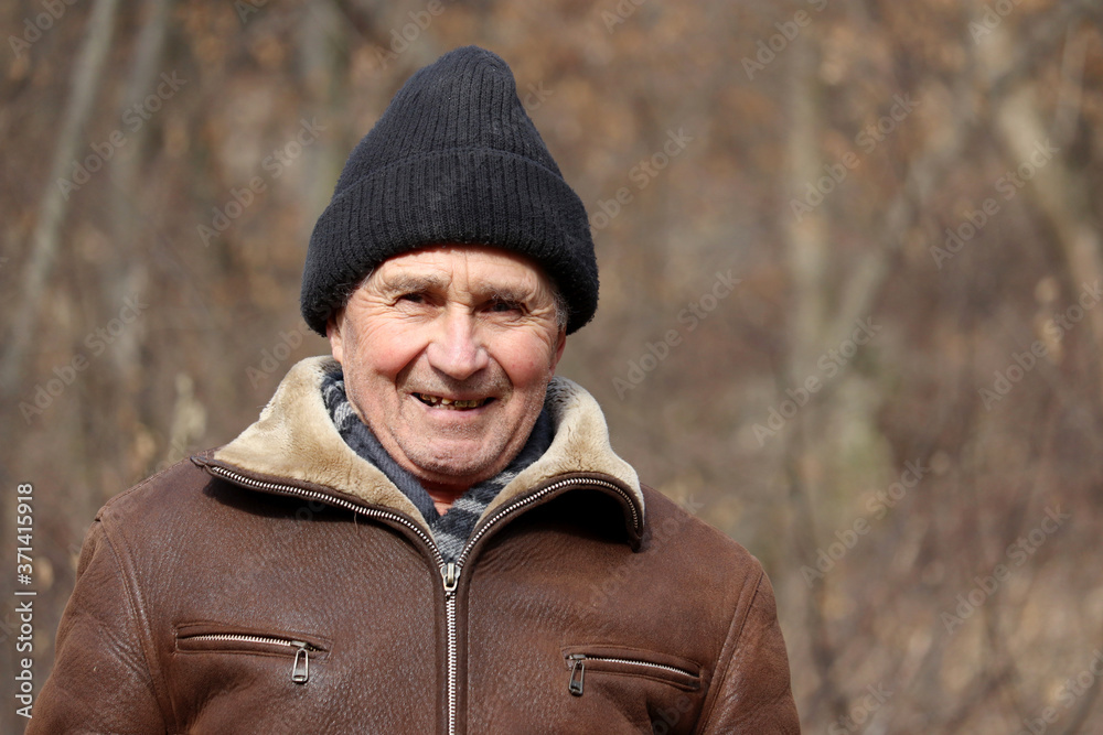 Portrait of happy elderly man standing in autumn park. Concept of old age, life in village Portrait of happy elderly man standing in autumn park. Concept of old age, life in village