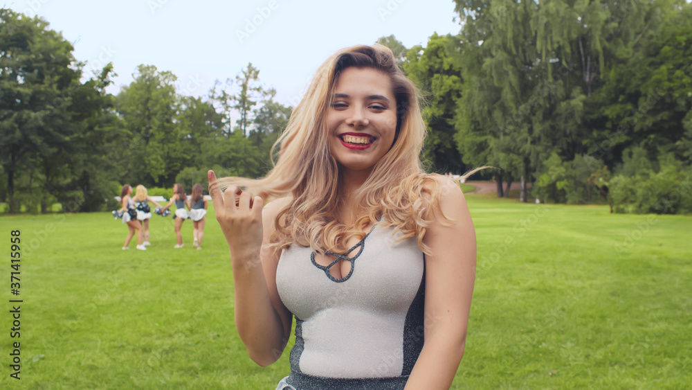 Portrait of beautiful young girl cheerleader smiling and touching hair posing at camera Portrait of beautiful young girl cheerleader smiling and touching hair posing at camera