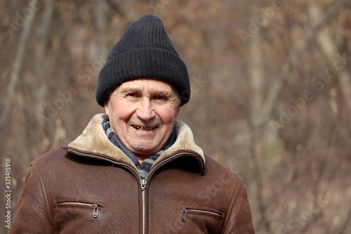 Portrait of happy elderly man standing in autumn park. Concept of old age, life in village © Oleg