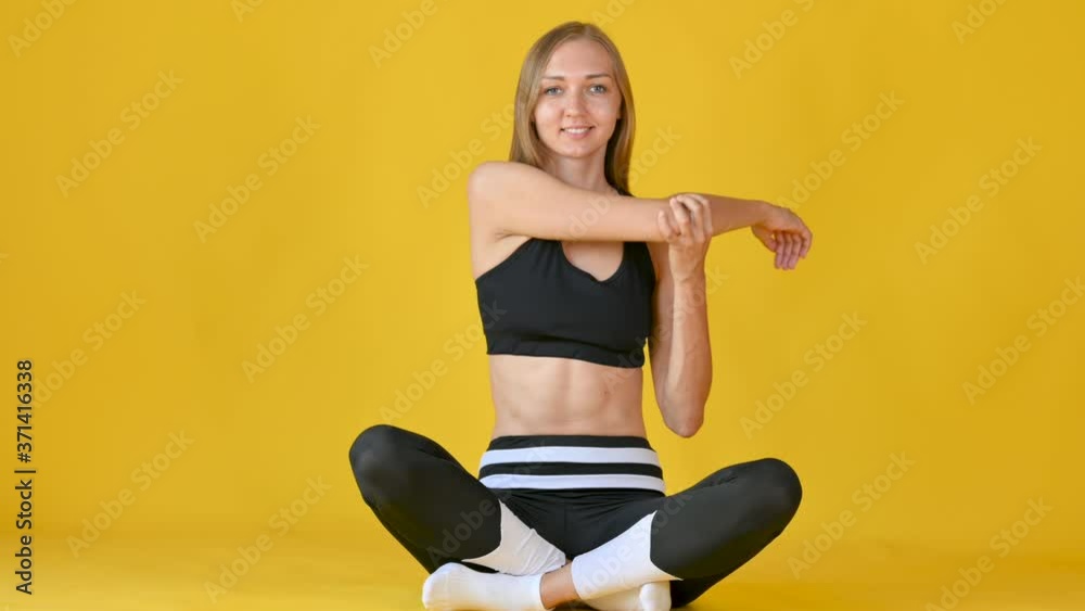 Female fitness training in sportswear Sitting on the Floor Isolated on a Yellow Background. fitness concepts. Female fitness training in sportswear Sitting on the Floor Isolated on a Yellow Background. fitness concepts.
