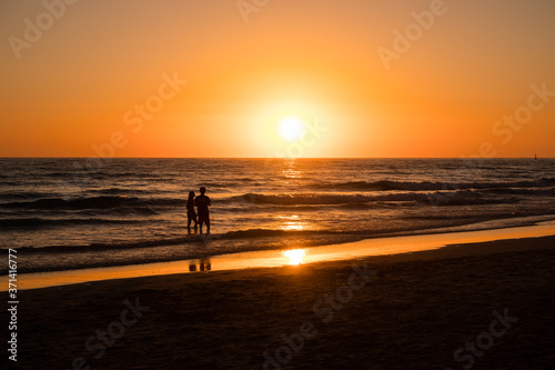 Silhouettes of people taking photos at sunset on the beaches of Cadiz, Spain
