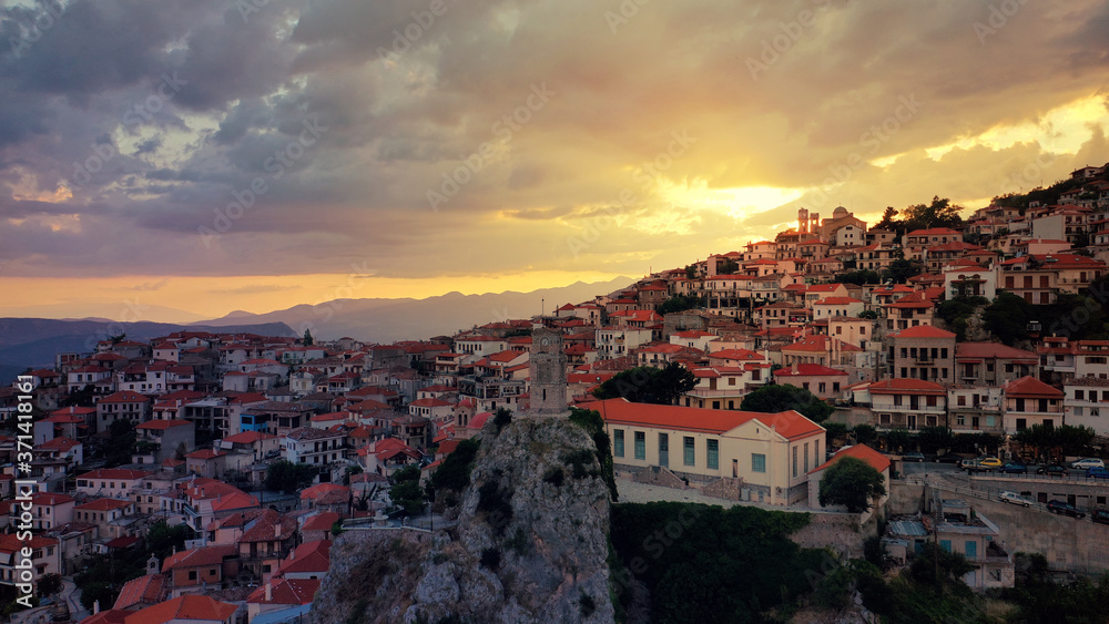 Aerial drone photo of beautiful sunset with golden colours and clouds over clock tower in picturesque and traditional village of Arachova, Viotia prefecture, Greece