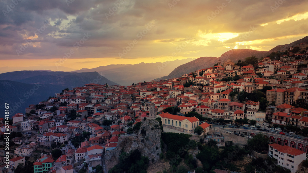 Aerial drone photo of beautiful sunset with golden colours and clouds over picturesque and traditional village of Arachova, Viotia prefecture, Greece