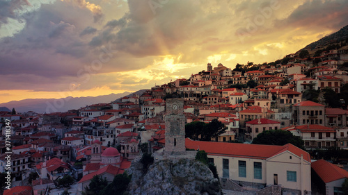 Aerial drone photo of beautiful sunset with golden colours and clouds over clock tower in picturesque and traditional village of Arachova, Viotia prefecture, Greece