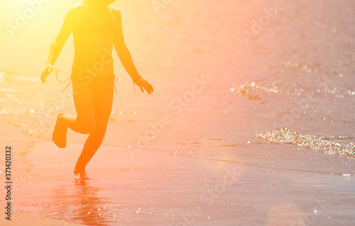 little kid runs at the shore against the rays of sun