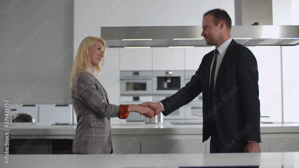 Side view of customer and consultant shaking hands in modern kitchen furniture showroom Side view of customer and consultant shaking hands in modern kitchen furniture showroom