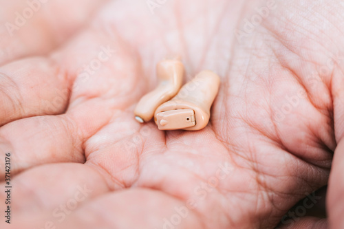 small intra channel hearing aid device in a man's hand