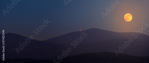 The full flower moon - May, 07, 2020. The rising moon over the mountain peaks of the Sudetes.