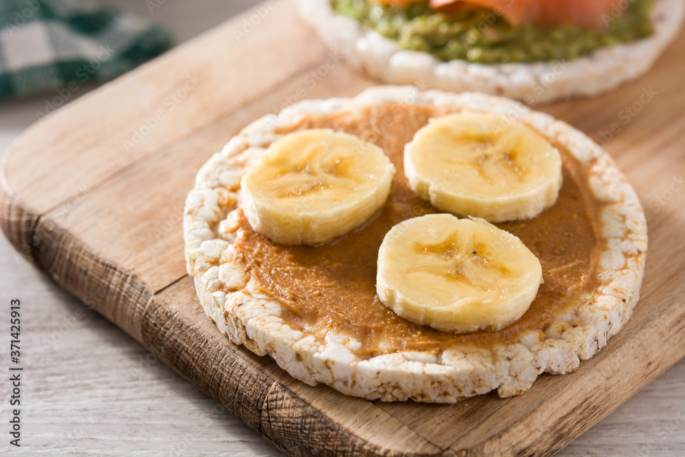 Puffed rice cake with banana and peanut butter on wooden table.	