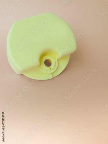 Vertical closeup of yellow-green box,holder,for orthodontic devices for kid,children and teenagers-for lip bumpers,aligner,dental plate and cap,for use with during braces on beige backdrop,copy space.