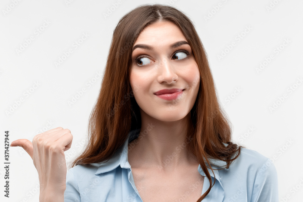 Beautiful girl with pointing and showing with thumb to the side with happy face, smiling. Presenting your product Beautiful girl with pointing and showing with thumb to the side with happy face, smiling. Presenting your product