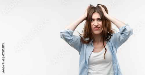 Photo of beautiful brunette female holding hands on head. Problems, surprise, fear, fobia concept