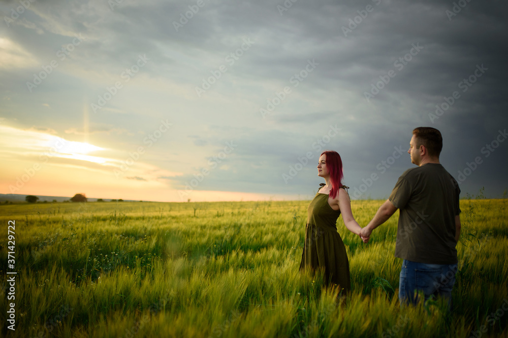 Young couple in a wheat field at sunset. Couple spend romantic time together.