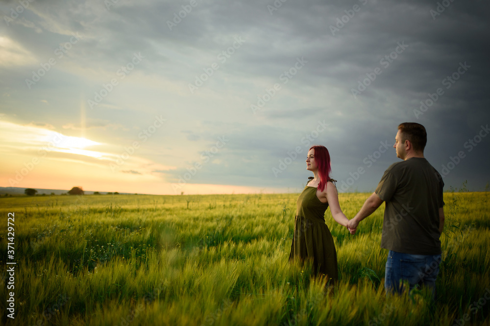 Young couple in a wheat field at sunset. Couple spend romantic time together. Young couple in a wheat field at sunset. Couple spend romantic time together.