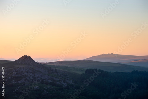 Absolutely stunning landscape image of Dartmoor in England showing Leather Tor and Kings Tor in majestic sunrise light