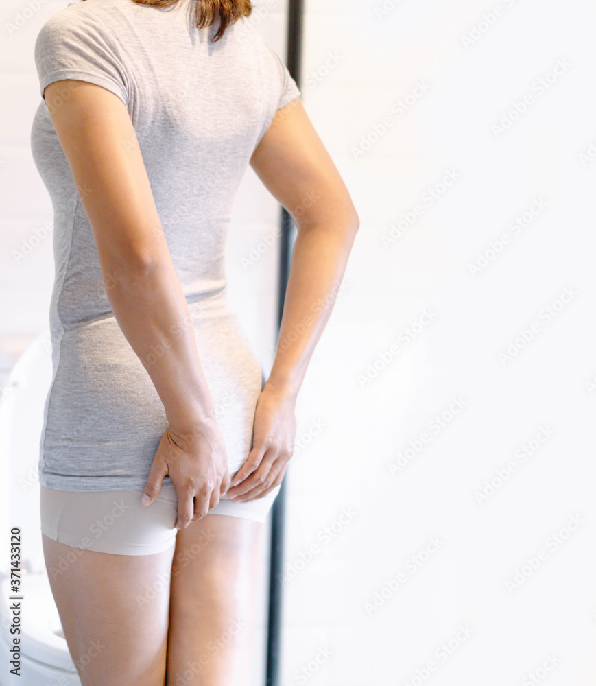 Closeup woman holding bladder with pee pain in the toilet, selective focus Closeup woman holding bladder with pee pain in the toilet, selective focus