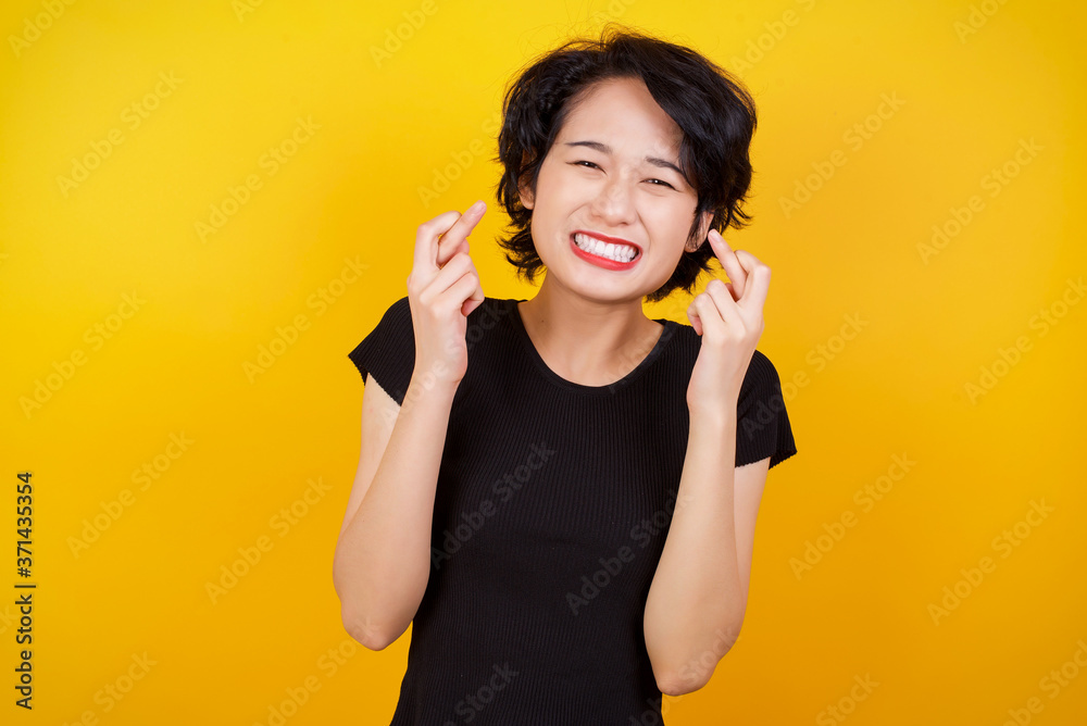 Beautiful young woman holding fingers crossed with worried expression hoping his boss didn't noticed her mistakes at work. Beautiful young woman holding fingers crossed with worried expression hoping his boss didn't noticed her mistakes at work.