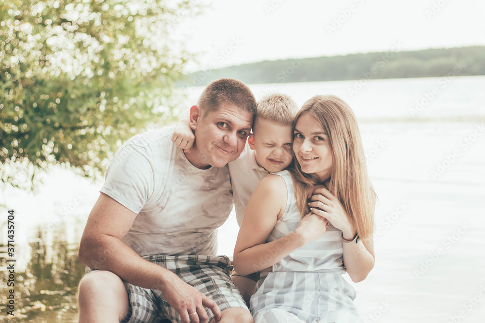 Naklejka premium Mom dad and son are sitting in nature near the shore