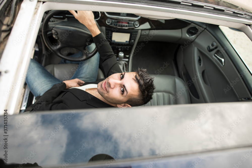Young driver looks through the roof of his car Young driver looks through the roof of his car
