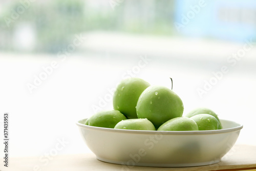 Foto Ripe green apple raw fruit in white bowl on wooden table, healthy organic fresh